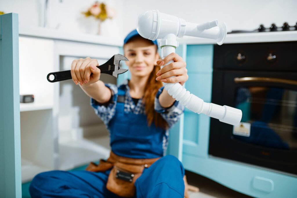Young Female Plumber Shows Wrench And Pipe.jpg
